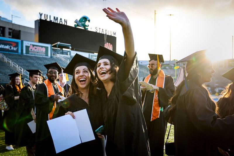 Graduates wave to family and friends in stands at Yulman Stadium