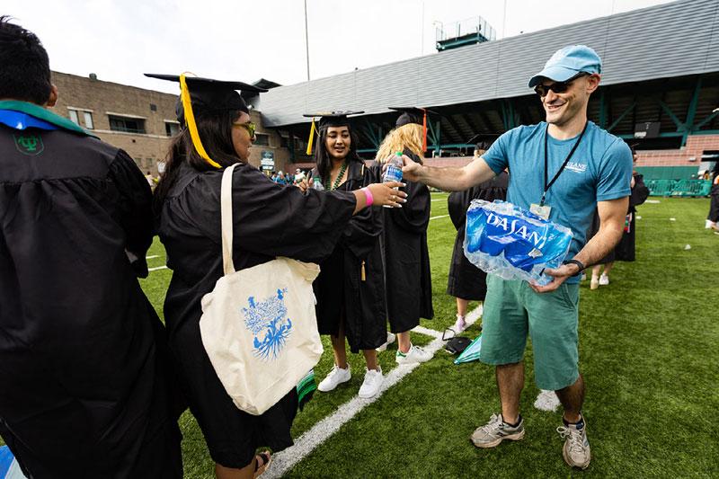 Volunteer hands out water bottles to graduates